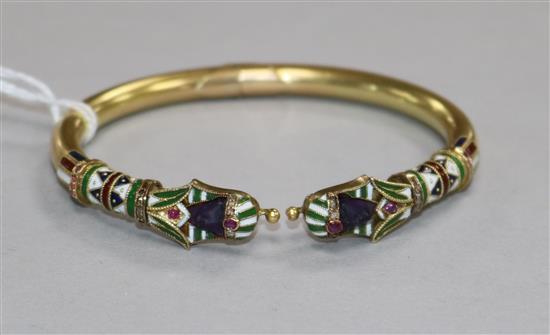 An Egyptianesque yellow metal, enamel and gem set hinged bangle.